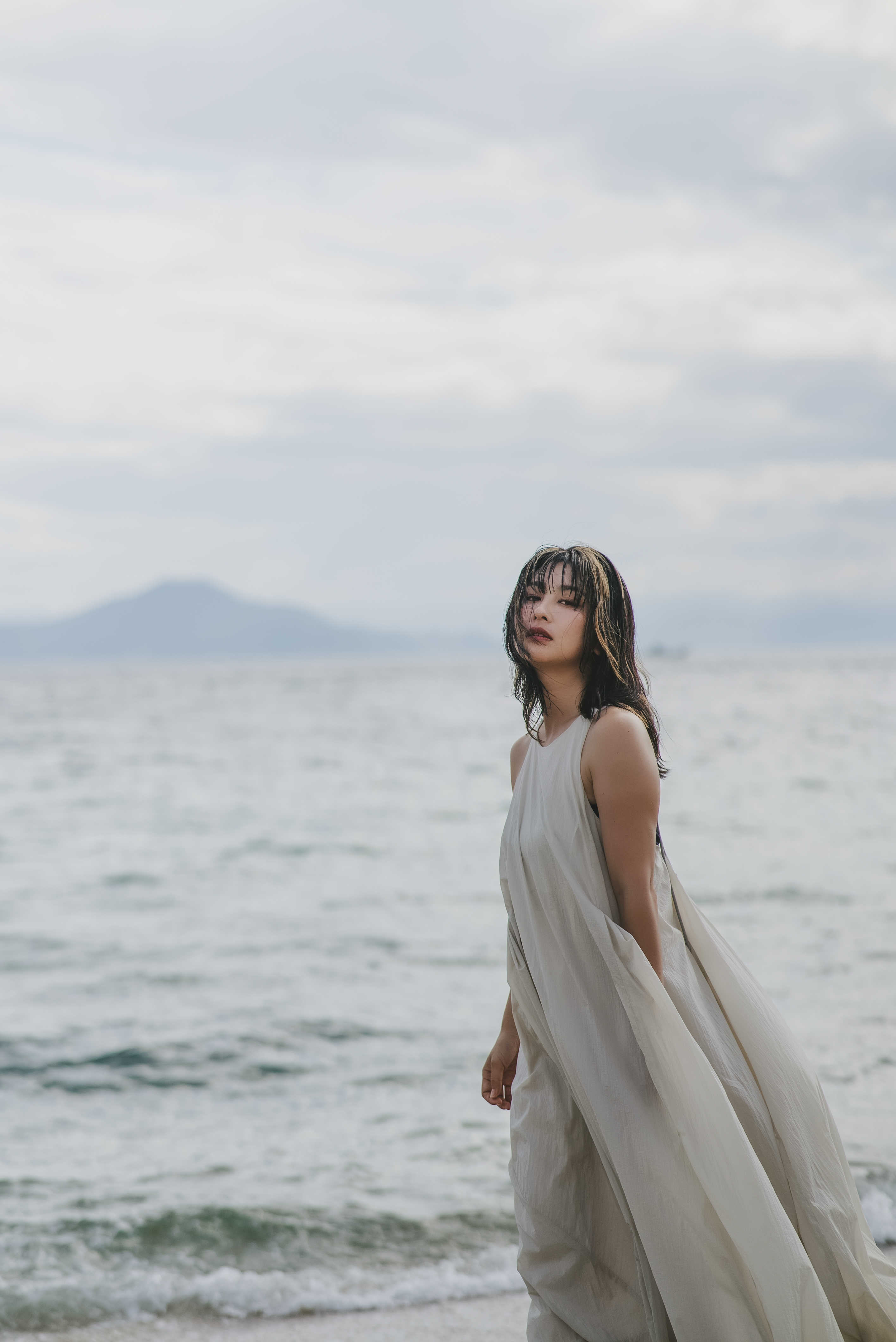 海辺に立つ白いドレスの人物ポートレート